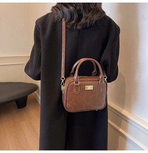 Detail of dark brown vintage crossbody bag showing golden metal clasp and vegan leather texture