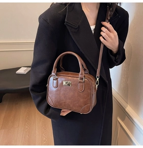 Detail of vintage brown crossbody bag featuring golden hardware and leather texture