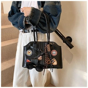 Detailansicht der Retro-Abzeichen und Anhänger an einer schwarzen Kunstleder-Reisetasche