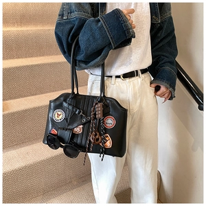 Detail einer schwarzen Ledertasche mit Vintage-Badges, Quaste und Sonnenbrillentasche