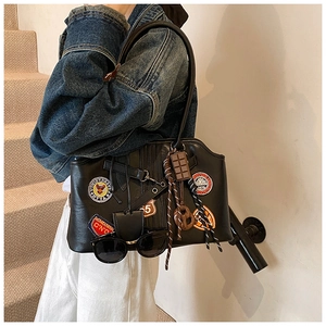 Detailansicht der schwarzen Ledertasche mit Stickereien und verspielten Anhängern