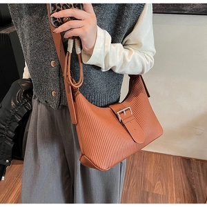 Close-up of brown pleated leather texture and silver buckle on a stylish shoulder bag