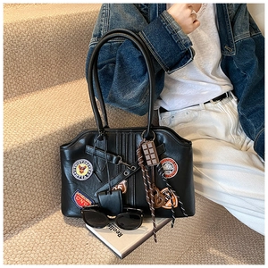 Detail der schwarzen Vintage-Tasche mit Retro-Abzeichen und Schokoladenanhänger