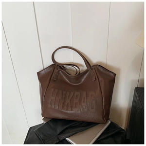 Dettaglio della grande borsa tote in pelle PU marrone scuro con lettere in rilievo