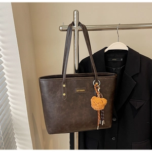Detailansicht der dunkelbraunen Leder-Shopper-Tasche mit Markenlogo und Bären-Anhänger