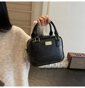 Detailed view of the black retro handbag showing golden metal feet and premium PU texture