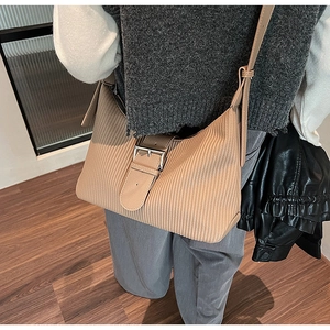 Detail of light brown pleated leather shoulder bag featuring a vintage buckle strap