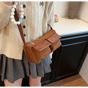 Brown faux suede baguette bag detail with utility pockets and a decorative white bead chain