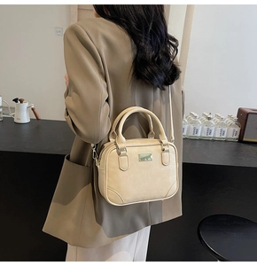 Beige crossbody small square bag shown on model with green blazer in minimalist setting