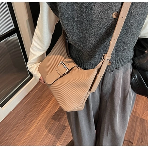 Detail of khaki pleated crossbody bag featuring textured folds and metal buckle strap