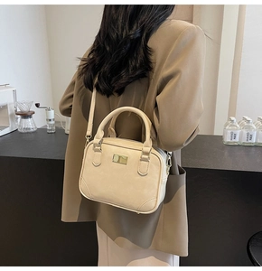 Detailed back view of a beige rectangle crossbody bag with gold plate and top handle