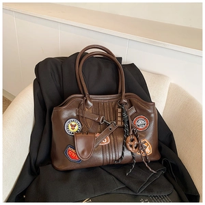 Detail der braunen Vintage-Tasche mit bestickten Aufnähern und Anhängern in Food-Optik