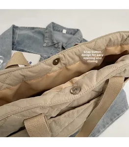 Gros plan sur le fermoir magnétique d'un sac cabas en nylon matelassé avec anses en toile