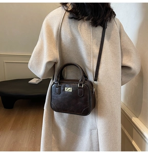 Detail of dark brown vintage small square bag with top handle and gold hardware detail