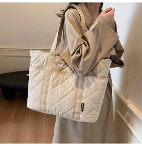 Détail du grand sac cabas matelassé beige avec poches avant et motif de couture en losange