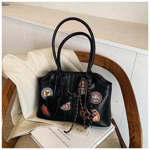 Details der schwarzen Vintage-Schultertasche mit Abzeichen und Anhängern