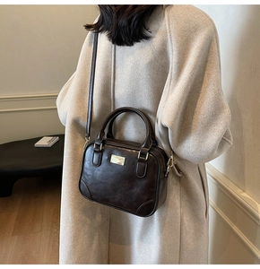 Detail view of dark coffee retro leather handbag styled with a cream winter coat
