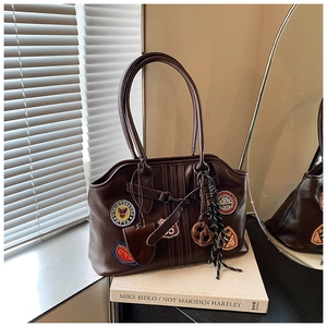 Detailansicht der braunen Retro-Ledertasche mit Vintage-Stickpatches und Doppelgriffen
