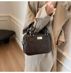 Detail of dark brown leather handbag styled with a classic trench coat for a retro look