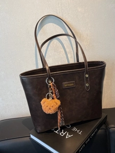 Große dunkelbraune Tote Bag mit Metall-Logo und süßem orangefarbenem Bären-Anhänger