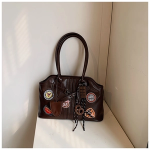 Detail der dunkelbraunen Retro-Handtasche mit Stickereien und Schoko-Anhänger