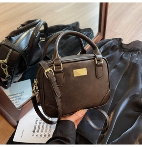 Macro detail of vintage brown leather square bag with golden hardware and mirror reflection