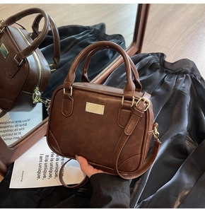 Close-up of a vintage brown leather handbag with golden hardware and zipper detail