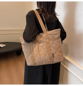 Détail d'un sac cabas matelassé kaki avec coutures en losanges et étiquette de marque