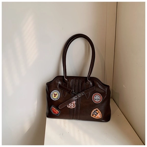Detailaufnahme der braunen Retro-Handtasche mit farbigen bestickten Aufnähern aus Kunstleder
