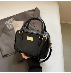 Detailed macro of black faux leather bag with elegant golden rectangular metal hardware
