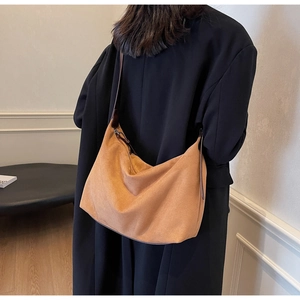 Braune Hobo-Tasche aus Wildleder mit großem Fassungsvermögen über einem schwarzen Blazer