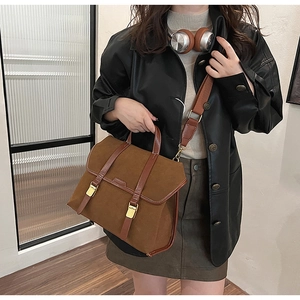 Close-up of caramel suede satchel with dark brown leather trim and golden metal buckles
