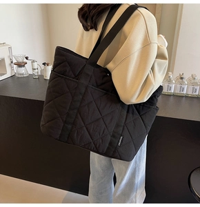 Détail d'un grand cabas matelassé noir porté par un mannequin dans un cadre moderne
