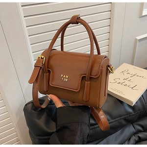 Detail of vintage brown leather handbag featuring gold metallic logo and double handles