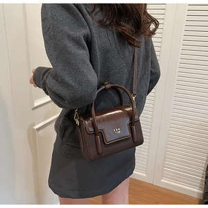 Detail of dark brown leather crossbody bag with PAN TOR logo and stylish handle