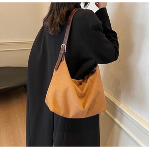 Detail der hobo-tasche aus karamellfarbenem wildleder mit dunkelbraunem lederriemen