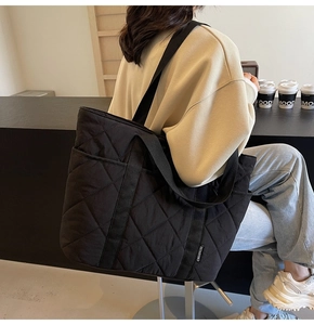 Gros plan d'un sac cabas noir matelassé avec bandoulière large et étiquette de marque