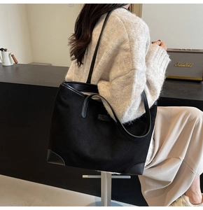 Detail einer schwarzen Shopper-Tasche mit Logo-Patch und verstärkten Leder-Ecken am Boden