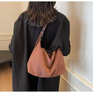 Nahaufnahme der karamellbraunen Wildledertasche mit silberner Schnalle am Mantel