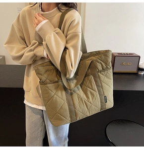 Détail d'un cabas matelassé vert olive avec larges anses en nylon porté par un mannequin