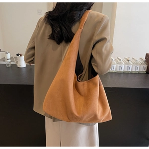 Sac hobo en daim marron porté à l'épaule dans le décor élégant d'un café
