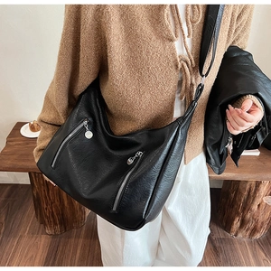 Détail d'un grand sac bandoulière en cuir noir avec deux fermetures éclair décoratives