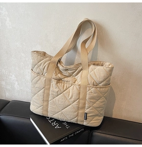 Gros plan du sac cabas matelassé beige avec surpiqûres en losange et poche latérale