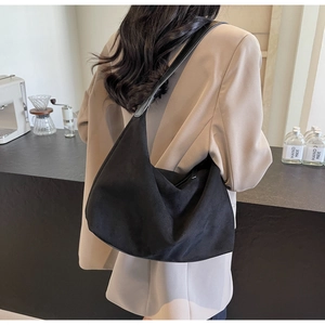Detail einer großen schwarzen Wildleder-Hobotasche kombiniert mit einem braunen Blazer