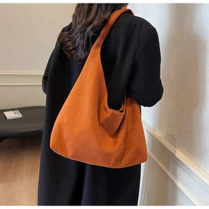 Vue détaillée d'un grand sac cabas en daim caramel porté sur un manteau d'hiver foncé