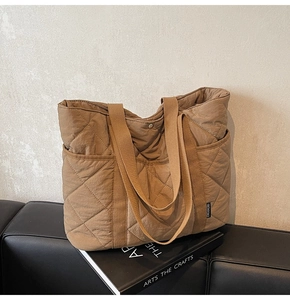 Vue détaillée d'un sac cabas marron matelassé avec poche latérale et étiquette de marque