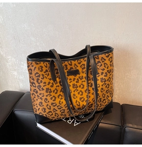 Detailansicht der Tragetasche mit Leopardenmuster und schwarzem Lederbesatz auf Ledersofa