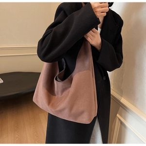 Gros plan détaillé d'un grand sac cabas en daim marron porté avec un manteau en laine noir