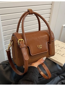 Brown vintage square handbag with glossy leather, dual handles and gold brand logo on cover