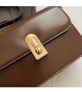 Macro shot of gold rectangular buckle and smooth brown leather on a vintage crossbody bag